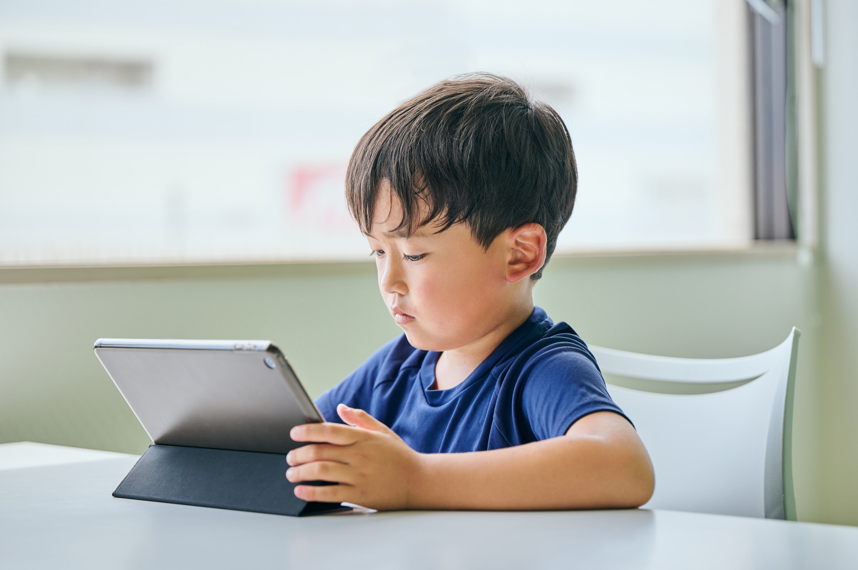 ノートパソコンの画面を見ている小学生